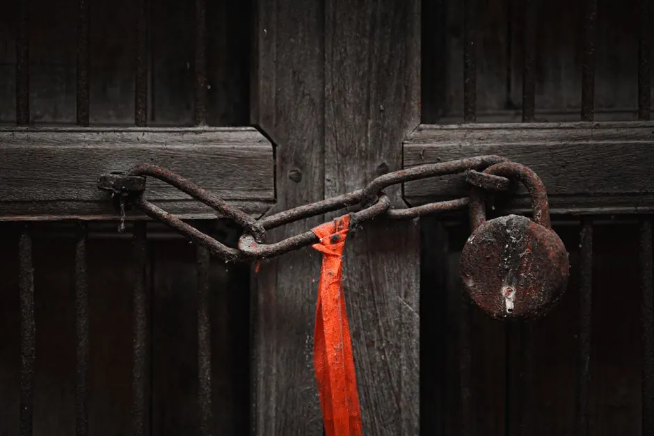 A rusty padlock and chain securing an old wooden door, symbolizing security and secrecy.
